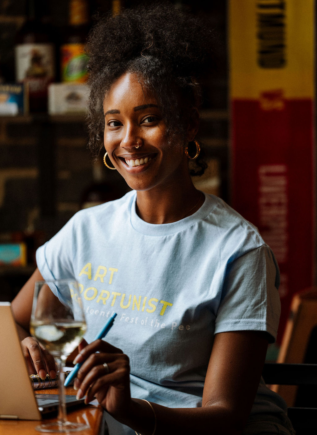 Terica Gary, a women with natural hair typing at a computer with a wine glass
